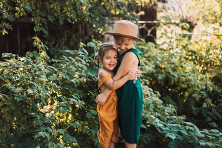 Brother and sister hugging in garden, green and yellow gardener overals, happy family.の写真素材