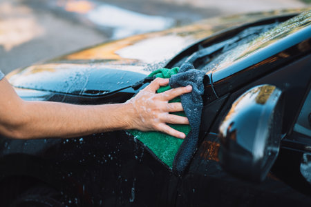 The guy wipes the car with soap rag.の写真素材