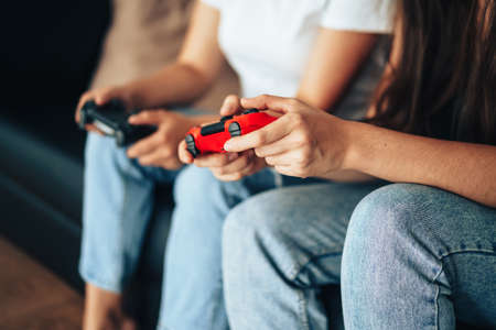 Girls holding gamepads and playing video games on the console.の写真素材