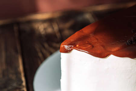 Piece of cake in white cream and brown glaze on wooden table.の写真素材