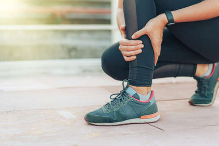 An athlete holds on to her injured leg on treadmillの写真素材