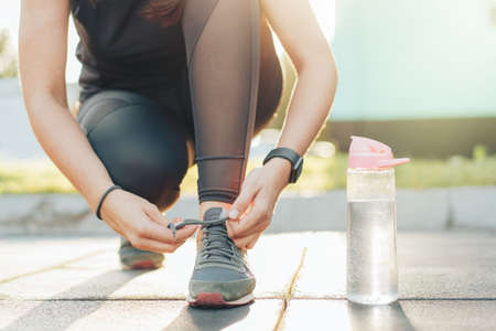 Girl in sportswear tying laces on sneakers.の写真素材