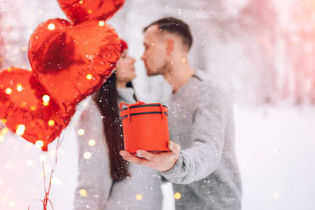 Guy giving gift with heart-shaped balloons to his girlfriendの写真素材