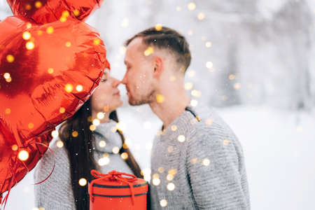 Guy giving gift with heart-shaped balloons to his girlfriend.の写真素材
