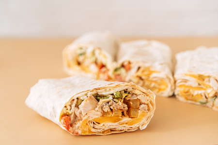 Four shawarma cutaway on beige background.