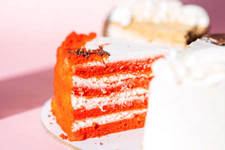 Piece of red velvet cake on pink background.