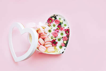 Macarons with flowers of different kinds in a box in the shape of a heart against a pink background. A gift for any occasion.の写真素材
