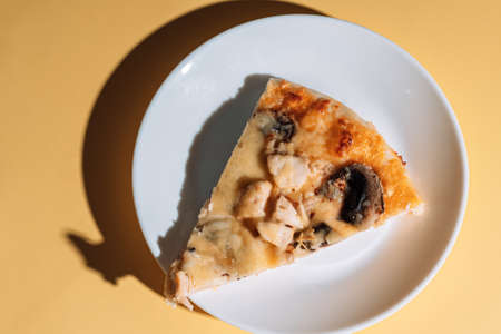 Slice of pizza with mushrooms and chicken on white plate.の写真素材