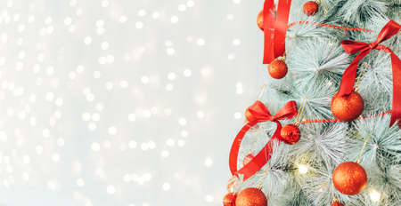 Christmas tree decorated with red bows and baubles against shiny background.の写真素材