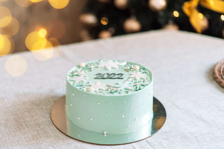 Turquoise christmas cake with 2022 written on white table.の写真素材