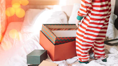 Child in striped pajamas standing next to open boxes.の写真素材