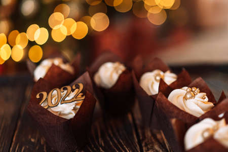 Celebration cupcakes in brown wrapper with 2022 sign on wooden table.の写真素材