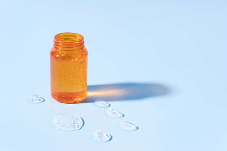 Brown jar of transparent serum on blue background.の写真素材