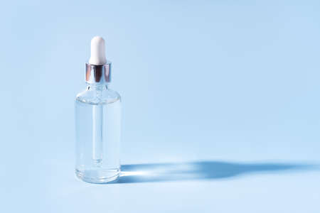 Glass jar with pipette of transparent liquid on blue background.の写真素材