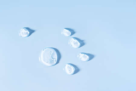 Six drops of clear serum on blue background.の写真素材