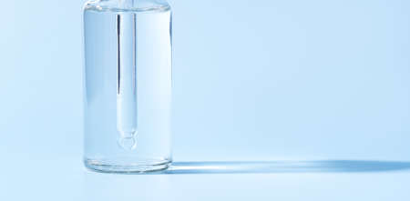 Glass jar with pipette of transparent liquid on blue background.の写真素材
