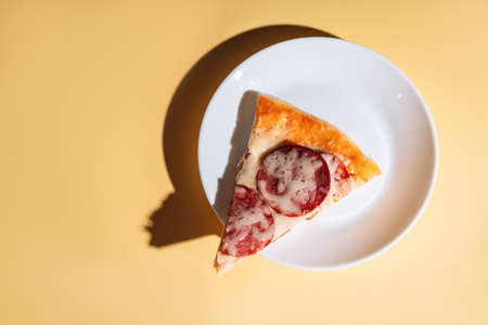 Slice of pizza with sausage on white plate.の写真素材