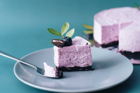 On blue plate piece of berry cheesecake with spoon on cyan backgroundの写真素材