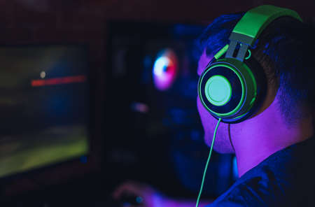 Guy playing video games in computer club under neon lightingの写真素材