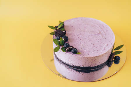 Berry and chocolate cheesecake with blueberries on yellow backgroundの写真素材