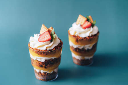 Puff cupcake in glass with strawberries on cyan backgroundの写真素材