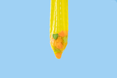 Yellow condom filled with small hearts against blue backgroundの写真素材
