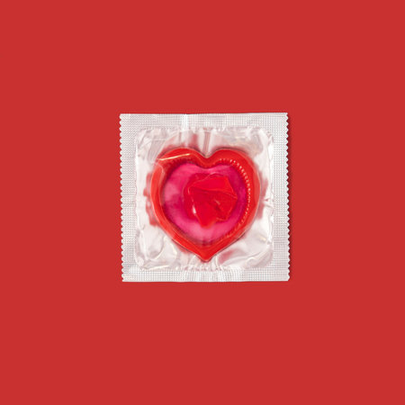 In the package, red condom in the shape of heart on red backgroundの写真素材