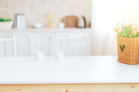 Wooden table with grass in front of blurred kitchenの写真素材