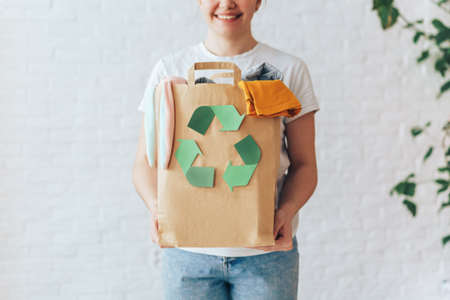 Girl holding paper bag with old clothes for recyclingの写真素材