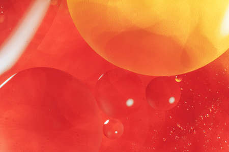Oil circles on the surface of the water against red background