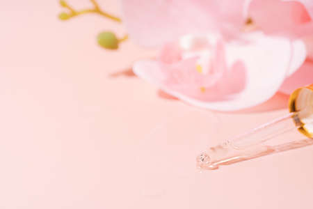 Orchid and pipette filled with liquid on pink backgroundの写真素材