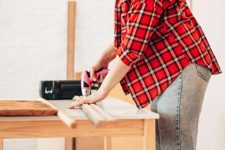 Girl in red shirt drills board with small drillの写真素材