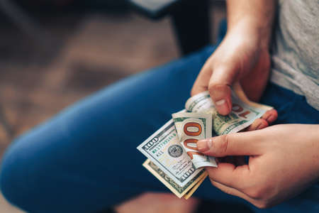 Man counts one hundred dollar bills in his hands