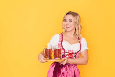 Woman in festive german dress holding tray of beerの写真素材