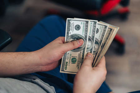 Man counts one hundred dollar bills in his handsの写真素材