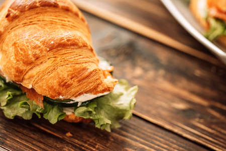 Croissant with red fish and salad on wooden tableの写真素材