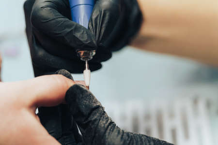 Manicurist processes nails with an electric fileの写真素材