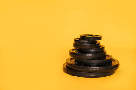 Stack of discs of different weights on yellow backgroundの写真素材