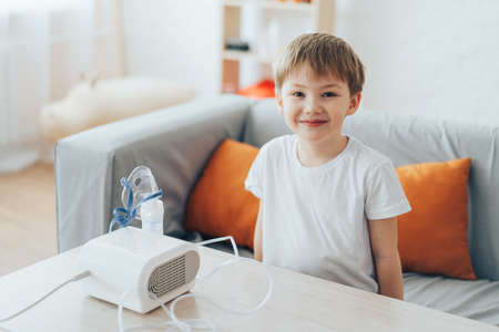 Little boy sitting on the couch in front of the nebulizerの写真素材
