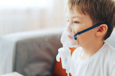 Little boy wearing nebulizer mask breathes asthma medicineの写真素材
