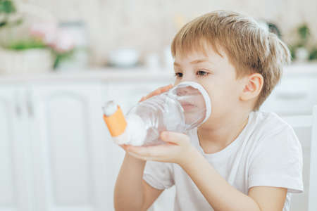 Little boy breathes with an inhaler through homemade spacerの写真素材
