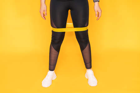 Girl in leggings with an elastic band on her legs against yellow backgroundの写真素材