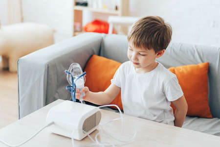 Little boy sitting at home holding nebulizer maskの写真素材
