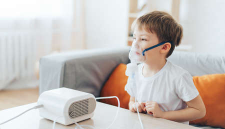 Little boy wearing nebulizer mask breathes allergy medicineの写真素材