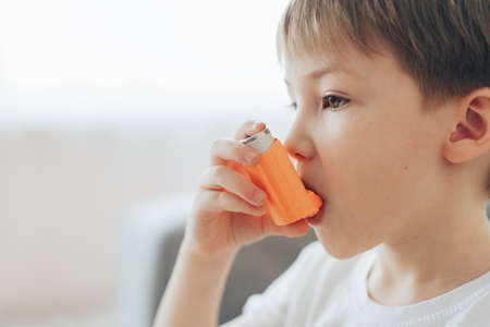 Little boy inhales medicine through an asthma inhalerの写真素材