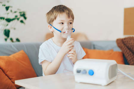 Little boy wearing nebulizer mask sitting on the couchの写真素材