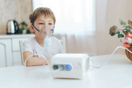 Little boy with mask from nebulizer sits at tableの写真素材