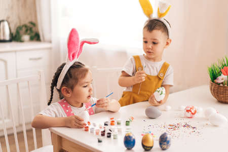 Funny Kids in bunny ears paint eggsの写真素材