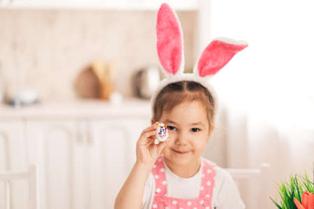 Child in rabbit ears holds decorated egg in his handsの写真素材