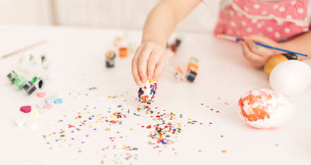 Little Child decorates Easter eggs with glitterの写真素材